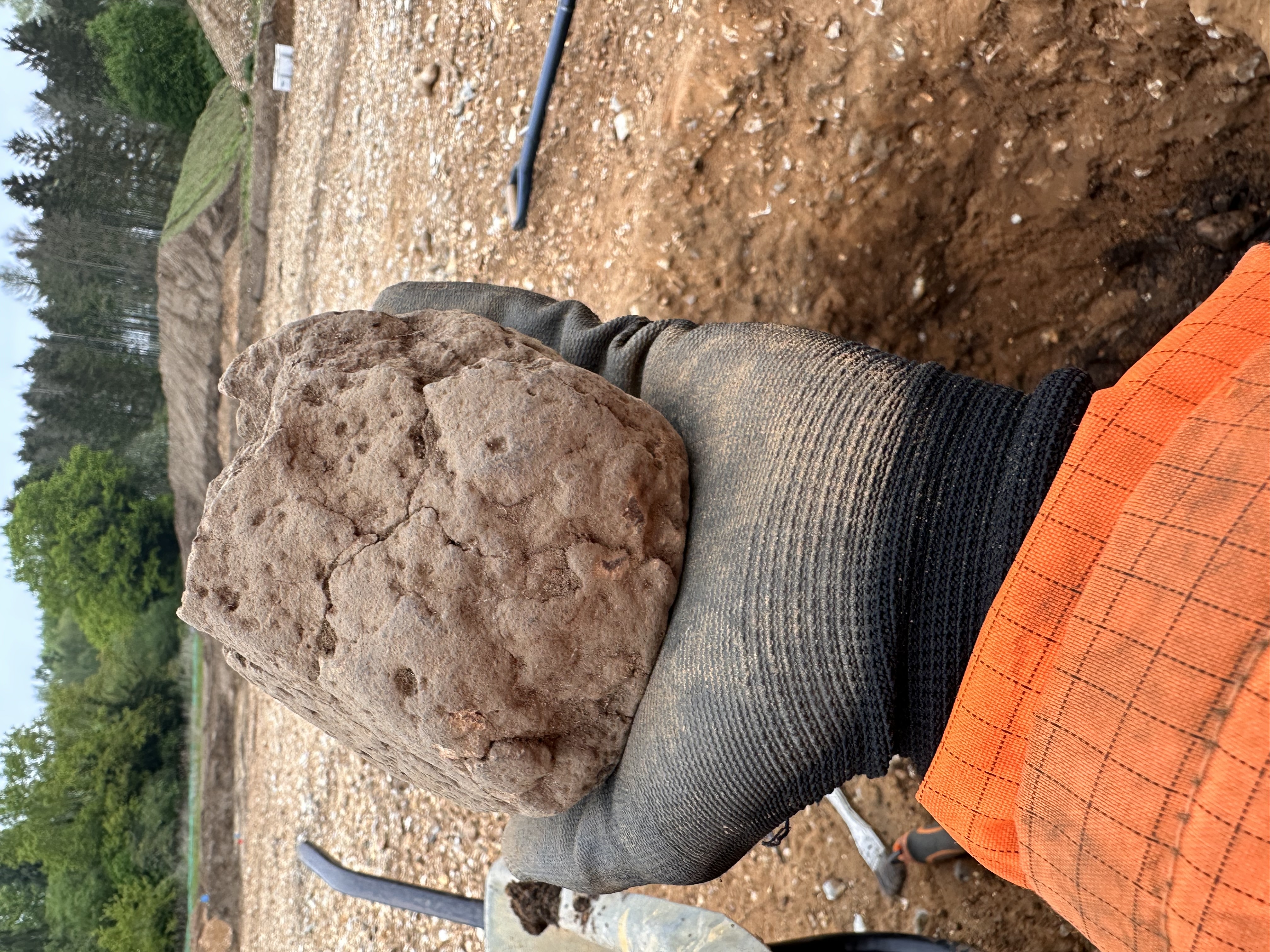 A lump of fired clay held in a gloved hand.