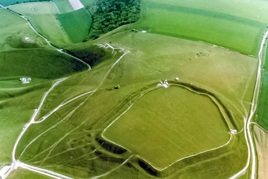 Aerial photo of Uffington Castle, an Iron Age hillfort that sits above the White Horse figure. The ramparts are clearly visible, as well as the Ridgeway, an ancient long-distance trackway, on the right of the hillfort. 