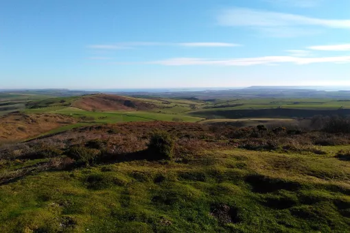 A view of a hilly landscape in the sunshine with clear blue skies.