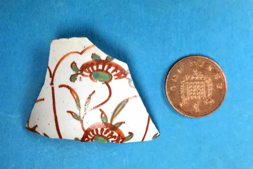 A pottery fragment with hand painted brown and green Chinese-style floral decoration