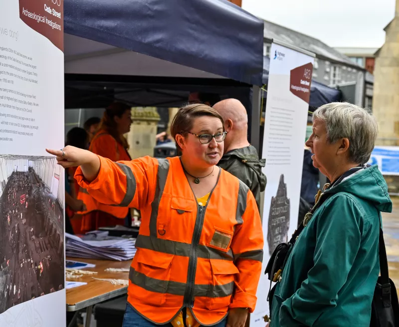 An archaeologist points out an outdoor display about Trinity Burial Ground in Hull