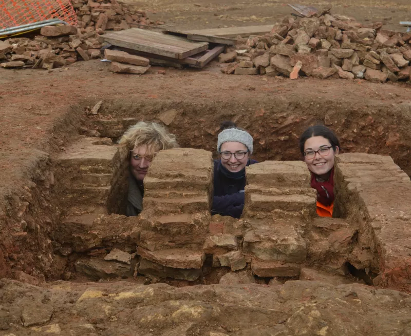 Image showing three archaeologists posing among the pilae (pillars or supports) of a Roman stucture uncovered near Corby.