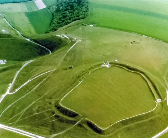 Aerial photo of Uffington Castle, an Iron Age hillfort that sits above the White Horse figure. The ramparts are clearly visible, as well as the Ridgeway, an ancient long-distance trackway, on the right of the hillfort. 